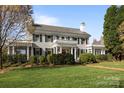 Two-story home with a lush green lawn, a chimney, manicured bushes, and mature trees at 1212 Queens Rd, Charlotte, NC 28207