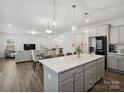 Modern open-concept kitchen with a large island, stainless steel refrigerator, and grey cabinets at 124 Benford Dr, Troutman, NC 28166