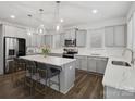 Modern kitchen featuring gray cabinets, stainless steel appliances, hardwood floors and a spacious island with seating at 124 Benford Dr, Troutman, NC 28166