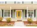 Inviting front porch with a vibrant yellow door, rocking chairs, and manicured landscaping at 1853 Beach Ln, Heath Springs, SC 29058