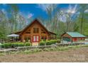 Inviting log cabin with a stone foundation, large windows, red front door, and detached garage at 528 Manchester Rd, Mount Gilead, NC 27306