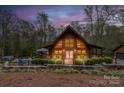 Charming log cabin with warm interior lights, a stone foundation, and a backyard pool area at 528 Manchester Rd, Mount Gilead, NC 27306