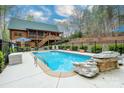 Backyard pool area of a log cabin featuring a pool, deck, landscaping, and black metal fencing at 528 Manchester Rd, Mount Gilead, NC 27306