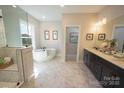 Bright bathroom featuring a soaking tub, dual vanities, and marble tile flooring for a luxurious experience at 7113 Fowley Rd # 0336, Charlotte, NC 28269