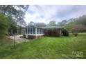 A brick home's backyard featuring a screened-in porch and lush lawn at 8608 Cedarbrook Dr, Charlotte, NC 28215