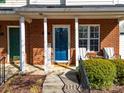 Inviting front porch with brick columns, a vibrant blue door, and a welcoming seating area with chairs at 107 Forester St, Mooresville, NC 28117