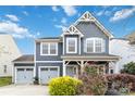Light blue two-story home featuring white trim, a two car garage, a well-manicured lawn, and flowers at 12706 Ballyliffin Dr, Pineville, NC 28134