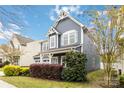 A charming two-story home with light blue siding, a cozy front porch, and colorful landscaping at 12706 Ballyliffin Dr, Pineville, NC 28134