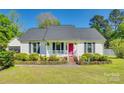 Charming single-story home boasts a manicured lawn, cheerful pink front door, and inviting front porch with seating at 2175 Highwood Rd, Rock Hill, SC 29732