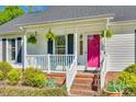 Close-up of a quaint porch with black shutters, a pink door, fern plants, and turquoise seating at 2175 Highwood Rd, Rock Hill, SC 29732