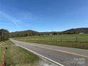 Expansive grassy fields meet rolling hills, creating a serene countryside view from the roadside at 236 Bowmans Cutover Rd, Taylorsville, NC 28681