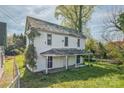 Two-story white home with an overhanging front porch and overgrown landscaping at 303 E Fisher St, Salisbury, NC 28144
