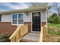 Close-up of the front door, emphasizing the wood trim, black door, and brick accents at 3791 Richard St, Claremont, NC 28610