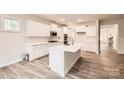 Bright kitchen with white cabinets, a large center island, stainless steel appliances, and wood-look flooring at 7009 New Town Rd, Waxhaw, NC 28173