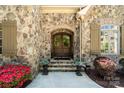 Charming stone facade featuring a wood front door with sidelights and decorative planters at 9011 Pine Laurel Dr, Weddington, NC 28104
