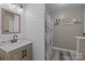Bathroom boasts shiplap walls, modern vanity, wood look flooring and shower with curtain at 2439 Heathershire Ln, Matthews, NC 28105