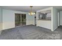 Open-concept living room and dining area with neutral carpet, slider doors to the backyard, and updated lighting at 6005 Fringe Tree Dr, Charlotte, NC 28227