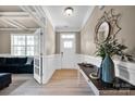 Bright foyer featuring hardwood floors, wainscoting detail, stylish mirror, and a glimpse into the living room at 704 Fresia Dr, Tega Cay, SC 29708
