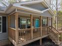 Close-up of the welcoming front porch with a cozy seating area and natural wood finishes at 7790 Caswell Rd, Stanley, NC 28164