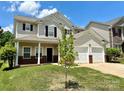 Welcoming two-story home with a front porch, two-car garage, and green lawn on a sunny day at 9419 Seamill Rd, Charlotte, NC 28278