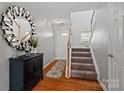 Welcoming foyer featuring wood floors, a decorative mirror and carpeted staircase at 10920 Walking Path Ln, Charlotte, NC 28213