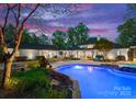 Inviting pool and outdoor living space with a stone patio, lush landscaping, and ample seating at 200 Highland Forest Dr, Charlotte, NC 28270