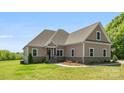 Attractive home with a mix of siding and stone, complemented by a lush green lawn and professional landscaping at 244 Alexis Lucia Rd, Alexis, NC 28006