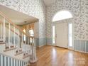 Inviting foyer with a staircase, light wood floors, soaring ceilings, and floral wallpaper at 2906 Crescent Knoll Dr, Matthews, NC 28105