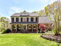Charming two-story brick home with a well-manicured front lawn, American flag, and mature trees at 5301 Greyfriar Ct, Waxhaw, NC 28173