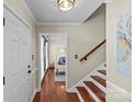 Inviting foyer with hardwood floors, a staircase with wooden rails, and a glimpse into a sunlit living space at 9637 Stoney Hill Ln, Charlotte, NC 28277