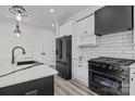 Modern kitchen with white cabinets, black appliances, stylish countertops and wood floors at 143 Mills Garden Rd, Statesville, NC 28625