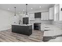 Modern kitchen featuring an island with stylish countertop, white cabinets, and wood floors at 143 Mills Garden Rd, Statesville, NC 28625