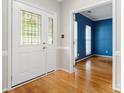 Bright foyer with hardwood floors, decorative glass door, and view of a blue accent wall at 15001 Arrowgrass Way, Charlotte, NC 28278