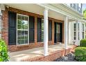 Close-up of the brick front porch featuring white columns and black shutters at 15001 Arrowgrass Way, Charlotte, NC 28278