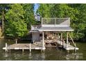 Multi-level boat dock and sun deck on a serene lake, surrounded by lush greenery and a glimpse of a house in the distance at 338 Fairfield Ct, Mount Gilead, NC 27306