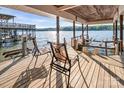 Relaxing lake view from a wooden dock with chairs and covered area featuring a boat lift at 338 Fairfield Ct, Mount Gilead, NC 27306