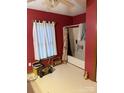 Bathroom with a toilet, window, and shower/tub with curtain and red painted walls at 1336 Mt Sinai Church Rd, Shelby, NC 28152