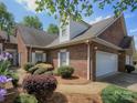 Charming brick home features a two-car garage and neatly landscaped yard with flowering bushes at 1520 Royalty Cir, Statesville, NC 28625