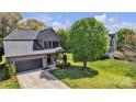Aerial view of a two-story home with stone accents and a driveway leading to the garage in a grassy yard at 1650 Berkshire Dr, Hickory, NC 28602