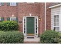 Charming brick home's front entrance features a green door with decorative hardware, sidelights, and green shrubbery at 301 Prairie Rose Ct, Waxhaw, NC 28173