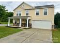 Inviting two-story home with a covered porch, stone details, and a spacious driveway leading to the garage at 4418 Palustris Ct, Charlotte, NC 28269