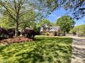 Beautifully landscaped front yard featuring lush greenery, mature trees, and a charming brick home at 4823 Antioch Church Rd, Weddington, NC 28104