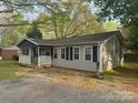 Single story home with light gray siding, black shutters, and front porch with white rails at 5319 Springdale Ave, Mint Hill, NC 28227