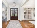 Elegant foyer with hardwood floors, decorative rug, and double glass doors at 6036 Foggy Glen Pl, Weddington, NC 28104