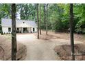 Exterior shot of the home nestled among mature trees and a long gravel driveway at 676 Chapel Hill Dr, Troy, NC 27371