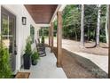 Inviting front porch with rocking chairs, wooden support columns, and stylish potted plants at 676 Chapel Hill Dr, Troy, NC 27371
