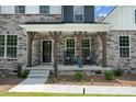 Inviting front porch with charming rocking chairs and stone accents, perfect for relaxing outdoors at 7001 New Town Rd, Waxhaw, NC 28173