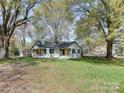 Exterior view of a lovely white home on a spacious lawn surrounded by mature trees at 1209 Mount Ulla Hwy, Mooresville, NC 28115