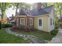 Charming home featuring a brick and siding exterior, complemented by a stone walkway and vibrant flower bushes at 1220 Oakwood Ave, Gastonia, NC 28052