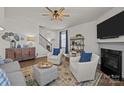 Cozy living room with a fireplace, plush seating, ceiling fan and staircase leading to the second floor at 15122 Lake Ridge Rd, Charlotte, NC 28278